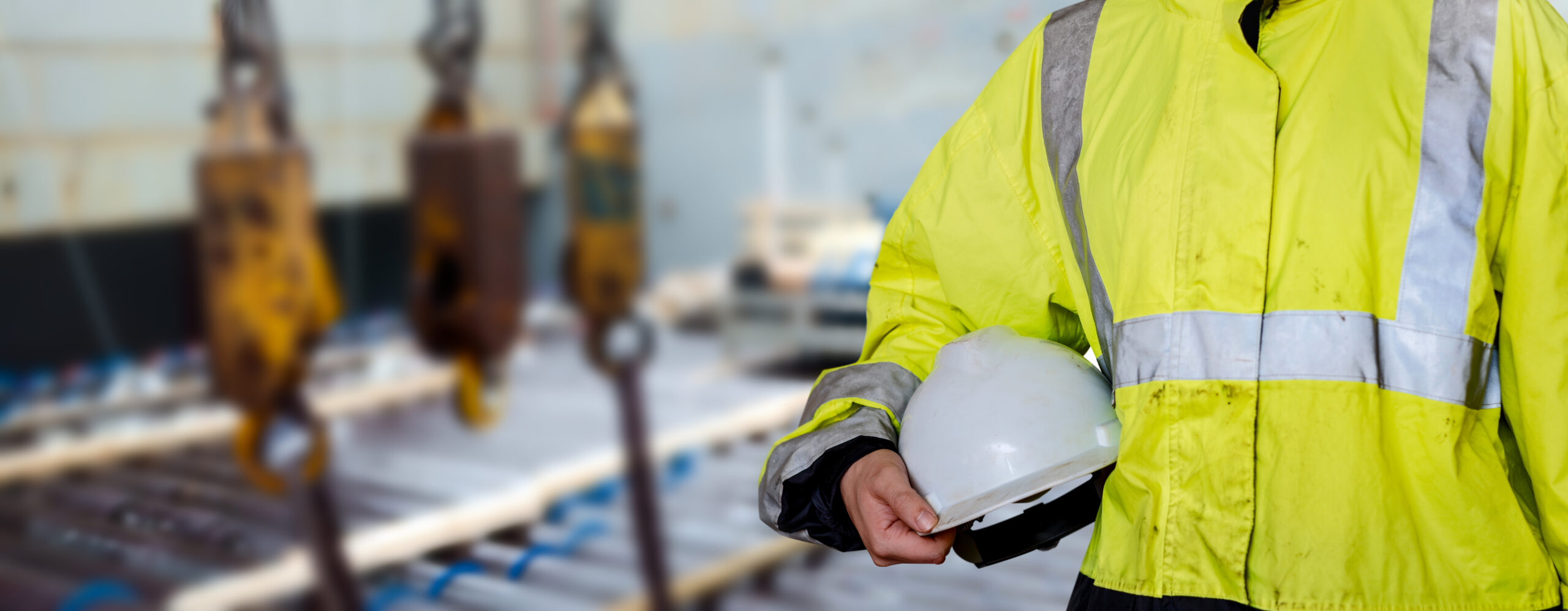 Ship supervisor engineer inspector stands at the dockside in a port. Wearing safety helmet and yellow vest. Cargo shipping industry. Protection and idemnity concept.